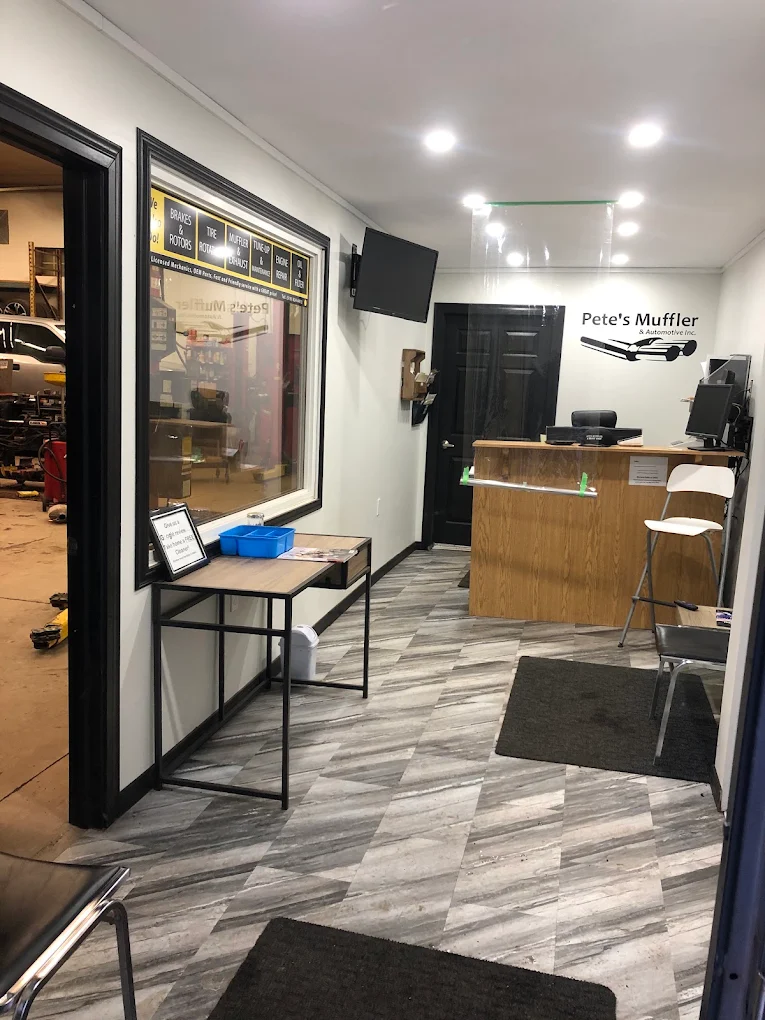 Front reception at Pete's Muffler & Automotive with the branded wall sign and a view through to the service bays