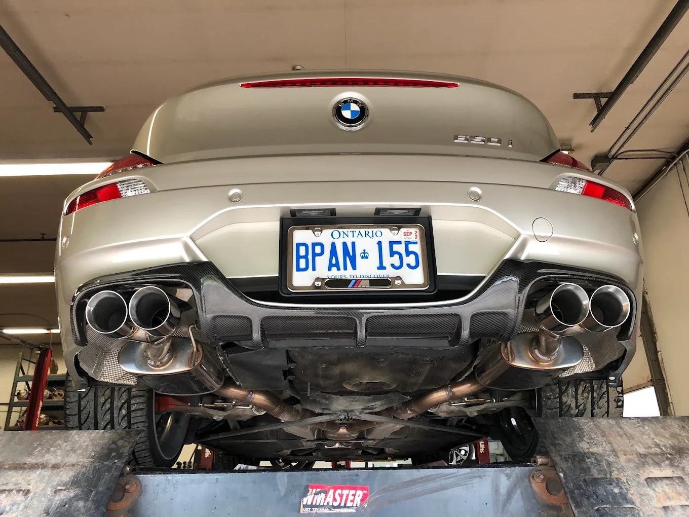 BMW Z4 rear end with quad stainless tips and a carbon diffuser, raised on the lift